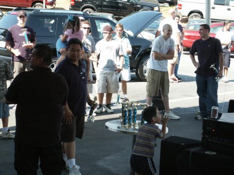 2001 Mercury Grand Marquis - Outdoor gathering with trophies and vehicles, likely a car show or community event.