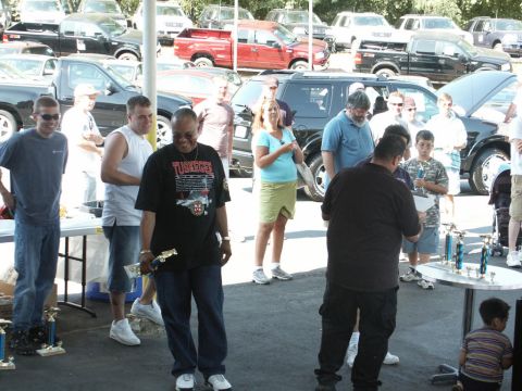 2001 Mercury Grand Marquis - Attendees and participants at an outdoor car show event, with trophies displayed on a table.