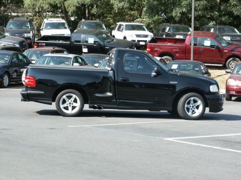 2001 Mercury Grand Marquis - A black pickup truck is parked in a lot with other vehicles.