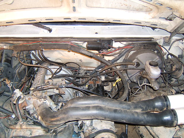 Engine bay with hoses, wires, and brake booster visible
