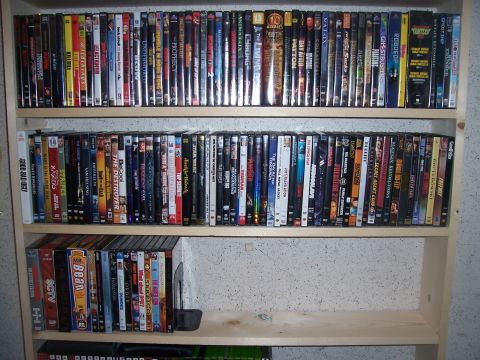 1995 Ford Bronco - A collection of DVDs is neatly organized on wooden shelves against a textured wall.