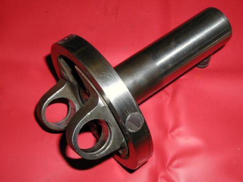 1967 Ford Ranchero - A metal driveshaft U-joint flange is shown against a red surface.