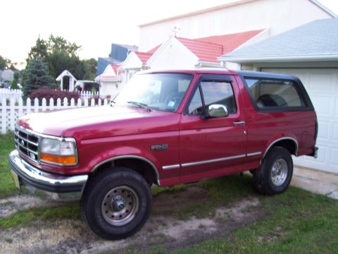 1995 Ford Bronco - This red 1995 Ford Bronco is parked in front of a garage.