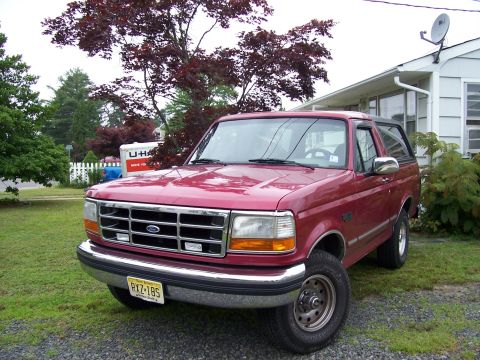 1995 Ford Bronco - This 1995 Ford Bronco is parked on a gravel driveway next to a lawn and a house.