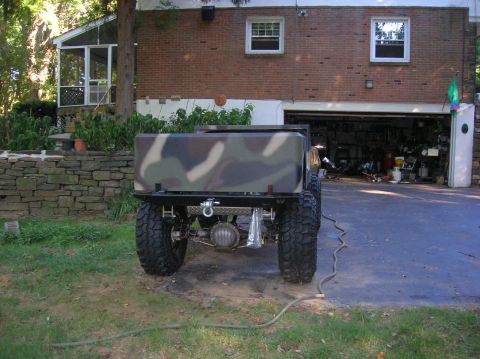 1979 Ford Bronco - This heavily modified vehicle's rear is visible, a camouflage bed and large off-road tires.