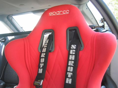 1993 Ford Probe - Interior view of a red racing seat Sparco branding on the headrest and Schroth harnesses.