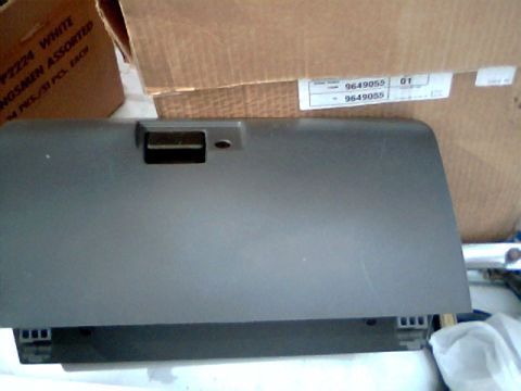 1992 Ford F-150 - A gray glove box door is shown in front of cardboard boxes. Part numbers are visible on a label in the background.