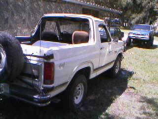 1986 Ford Bronco - A white 1986 Ford Bronco is parked outdoors under a covered area, with another vehicle visible behind it.