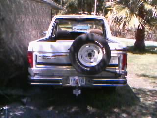 1986 Ford Bronco - Rear view of a white Ford Bronco, showing its spare tire and chrome bumper.