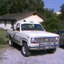 1986 Ford Bronco - This white pickup truck is parked outside a house on a sunny day.