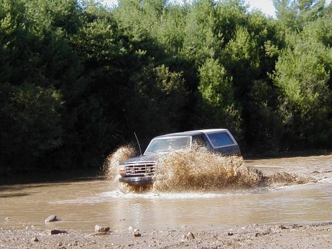 1993 Ford Bronco - This 1993 Ford Bronco is navigating a muddy water crossing with significant splash.