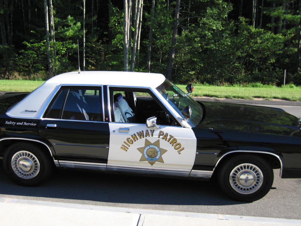 Close side view of black-and-white Highway Patrol sedan with door spotlight