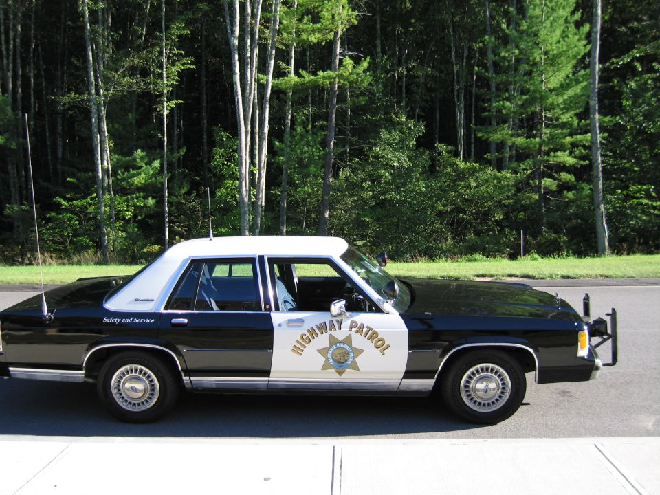 Side view of black-and-white Ford Highway Patrol sedan on paved road
