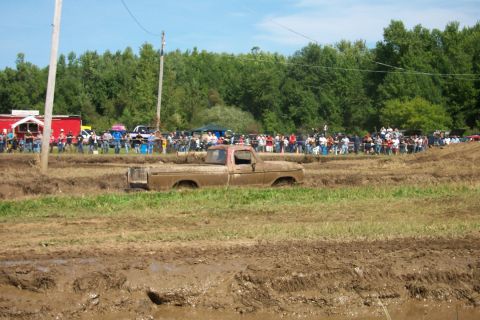 1979 Ford F-150 - A crowd watches as a pickup truck gets stuck in a muddy track during a competition.