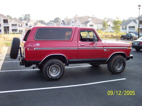1979 Ford Bronco - This red 1979 Ford Bronco is parked in a lot with apartment buildings in the background.