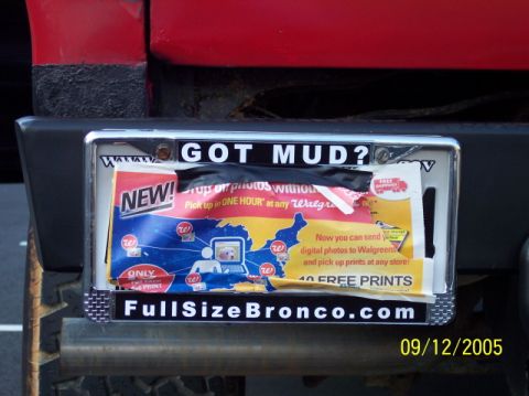 1979 Ford Bronco - A license plate frame on a red vehicle's bumper advertises 'FullSizeBronco.com' and 'GOT MUD?'.
