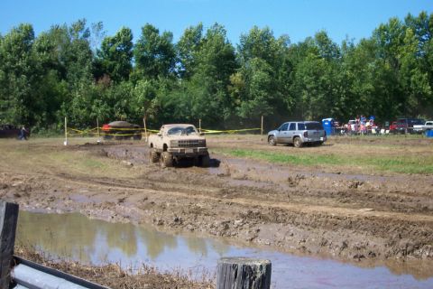1979 Ford F-150 - Off-road vehicles navigate a muddy course during a recreational event on a sunny day.