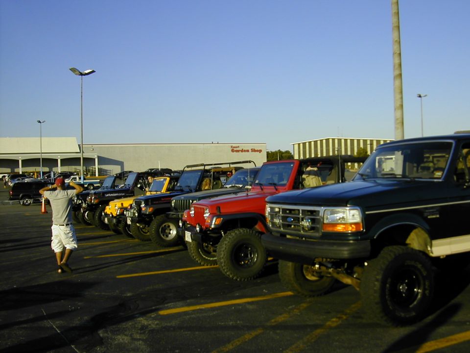 Dark green Ford Bronco with a white stripe, front 3/4 view, parked in a lot