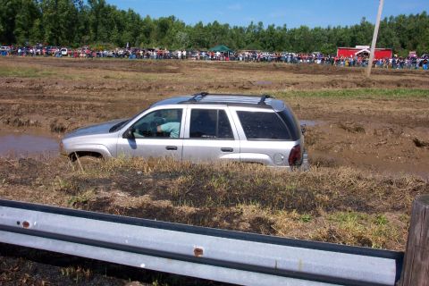 1979 Ford F-150 - SUV stuck in mud during an event, with a crowd watching in the distance.