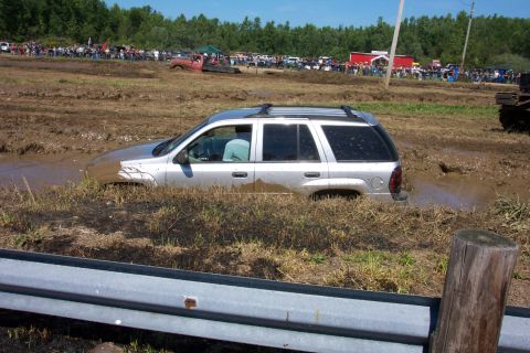 1979 Ford F-150 - SUV is stuck in a mud pit during an event with many people watching.