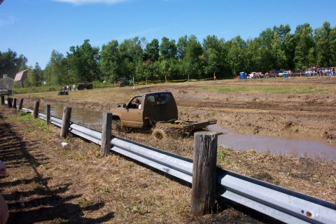 1979 Ford F-150 - A pickup truck navigates a muddy track, with spectators visible in the background.