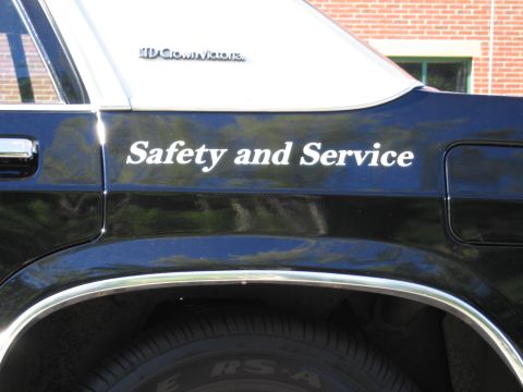 1991 Ford LTD Crown Victoria - Close-up of a black sedan's rear fender showing italic Safety and Service lettering and an LTD Crown Victoria badge above the wheel.