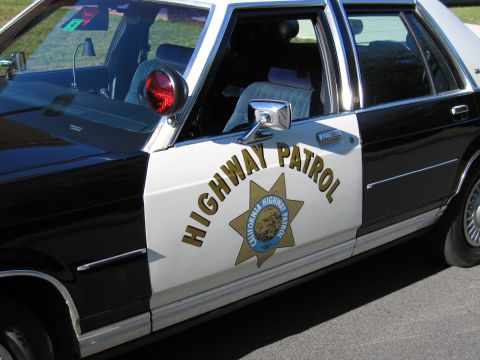 1991 Ford LTD Crown Victoria - Close view of a black-and-white police sedan's front door bearing HIGHWAY PATROL lettering and the gold California Highway Patrol star.