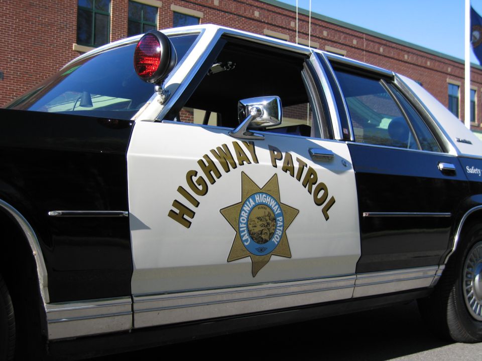 Front door of black-and-white CHP sedan by brick building