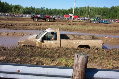 1979 Ford F-150 - A truck is stuck in the mud at an outdoor event with spectators watching.