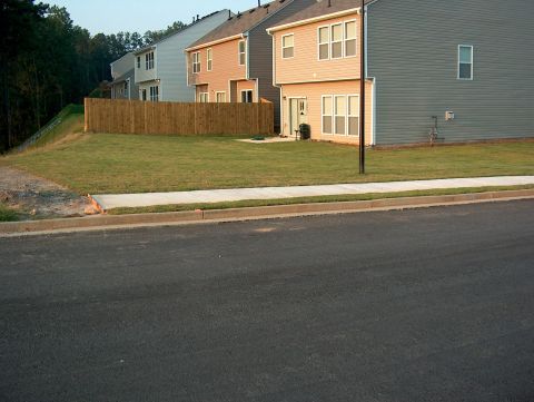 1998 Ford Taurus - A quiet residential street lined with houses and a well-maintained lawn.