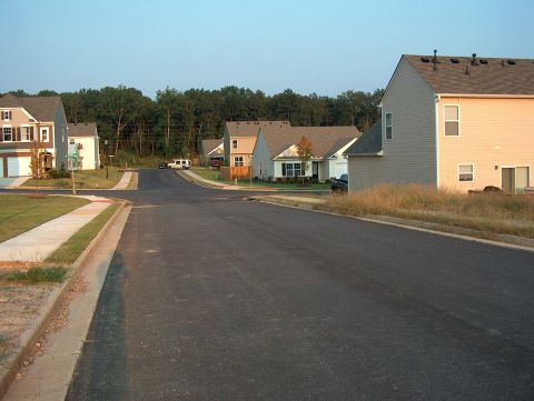 1998 Ford Taurus - A quiet street in a suburban neighborhood with houses under a clear sky.