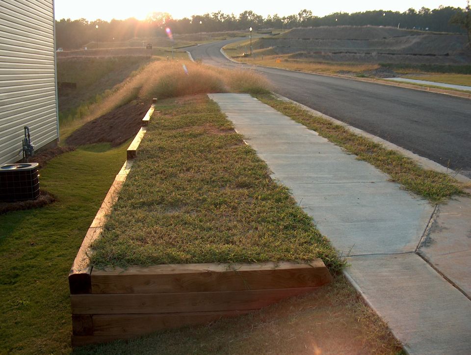 Suburban street with sidewalk and retaining wall at sunset