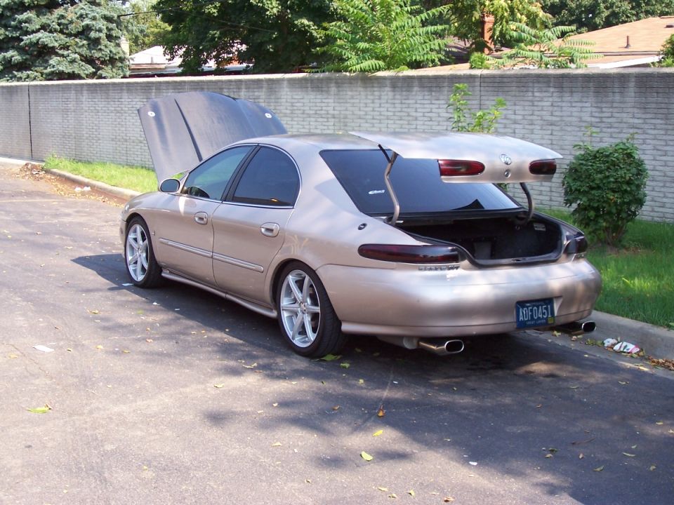 Gold Mercury Sable sedan with trunk and hood open, rear three-quarter view