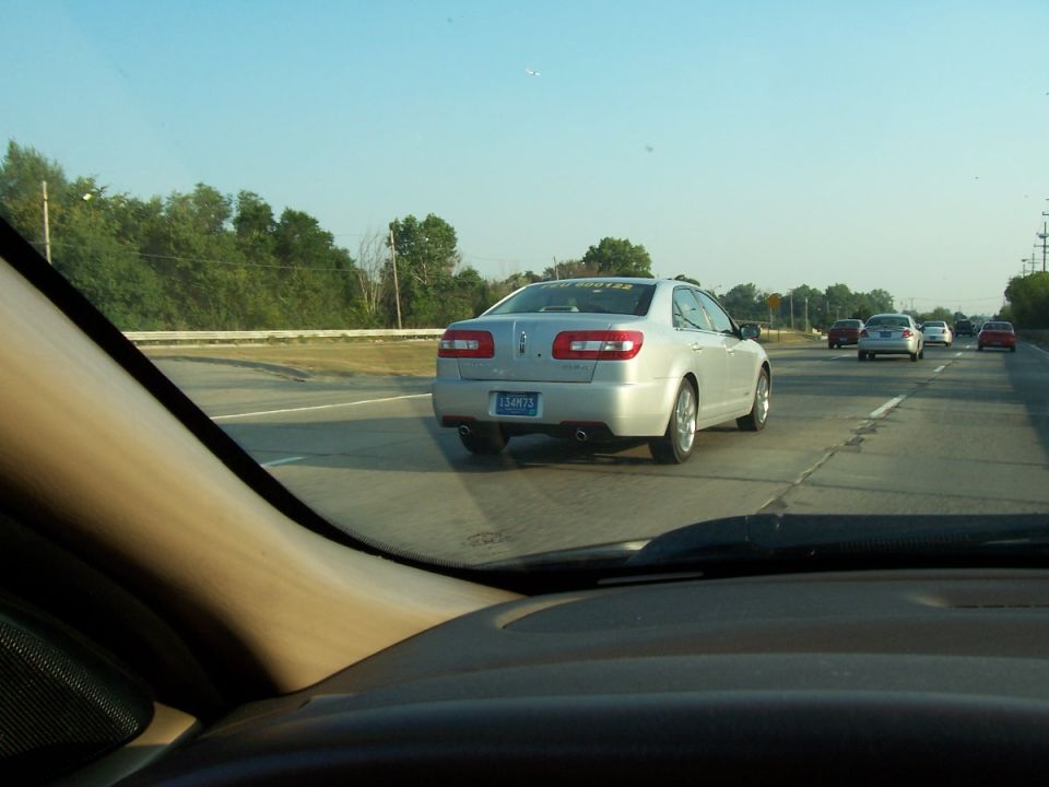 Silver Lincoln MKZ sedan ahead on a highway, seen through a windshield