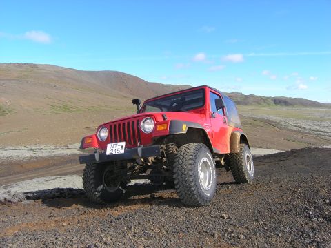 2001 Jeep Wrangler - A red 2001 Jeep TJ is parked on a rocky terrain under a clear blue sky.