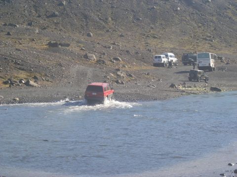 2001 Jeep Wrangler - Several vehicles are parked on a rocky shore while a red SUV drives through the water.