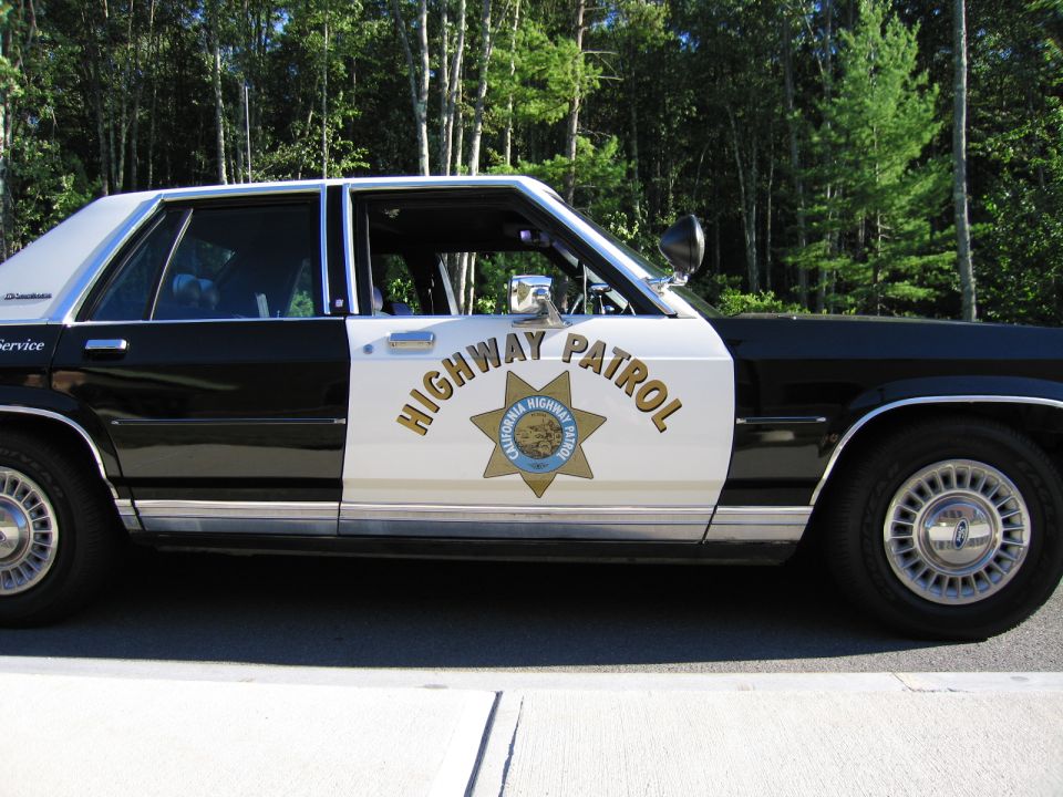 Profile of black-and-white sedan with HIGHWAY PATROL lettering and gold star