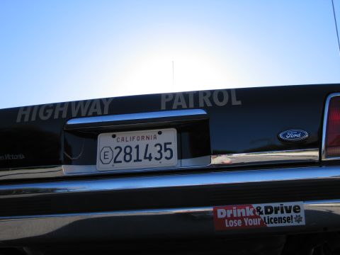 1991 Ford LTD Crown Victoria - Rear deck of a black Ford sedan showing HIGHWAY PATROL lettering, a Ford oval, and a California plate reading 281435.