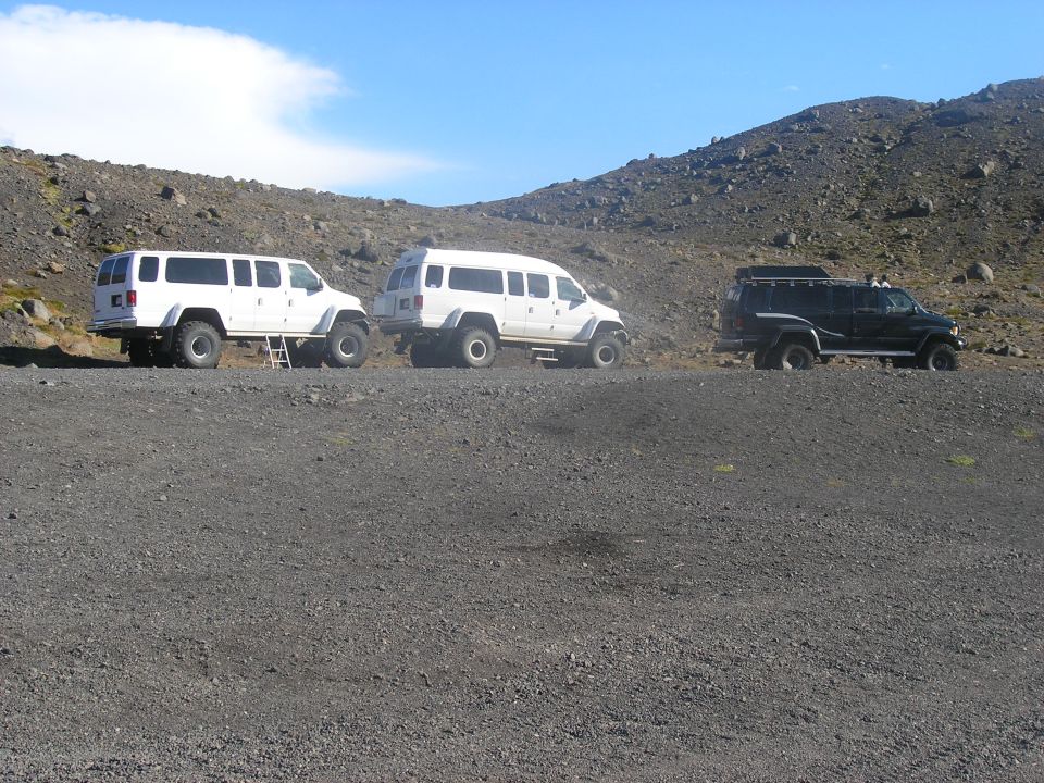 Three modified vans and SUVs on a rocky terrain