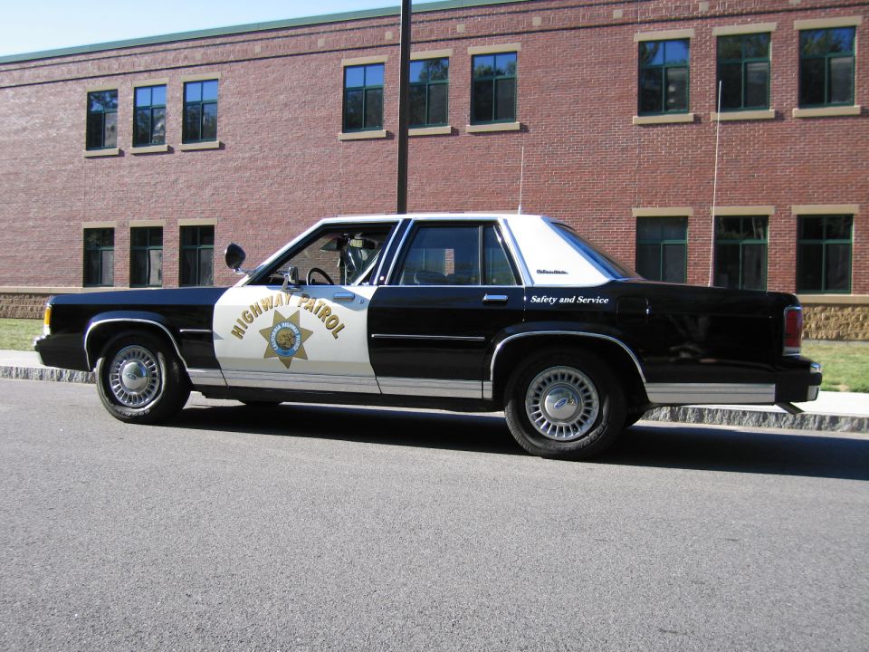Black-and-white police-style sedan parked by brick building