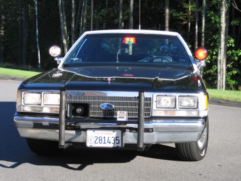 1991 Ford LTD Crown Victoria - Head-on view of a black Ford police-replica sedan showing the Ford grille emblem, push bumper, and California plate 281435.