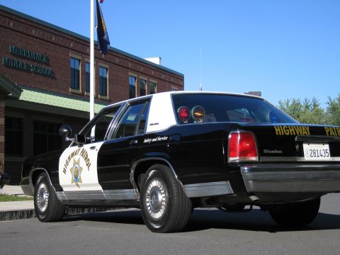 1991 Ford LTD Crown Victoria - Rear three-quarter view of a black-and-white Highway Patrol police sedan showing its roof light bar and rear Highway Patrol lettering.