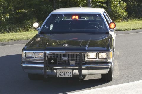 1991 Ford Crown Victoria - A 1991 Ford Crown Victoria police car is shown from the front, equipped with emergency lights and a push bumper.