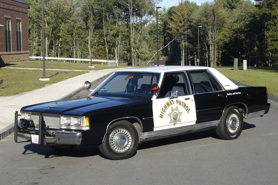 Black and white Ford Crown Victoria CHP replica cruiser, front 3/4 view with push bumper