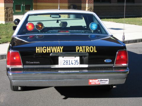 1991 Ford LTD Crown Victoria - Direct rear view of a black Highway Patrol sedan with red and blue roof beacons, an LTD Crown Victoria badge, and California plate 281435.