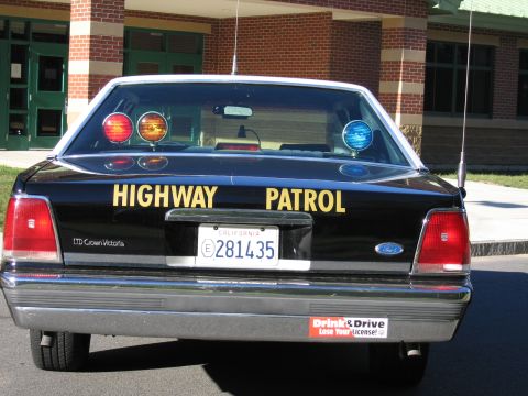 1991 Ford LTD Crown Victoria - Direct rear view of a black Highway Patrol LTD Crown Victoria sedan with illuminated red and amber roof beacons and California plate 281435.