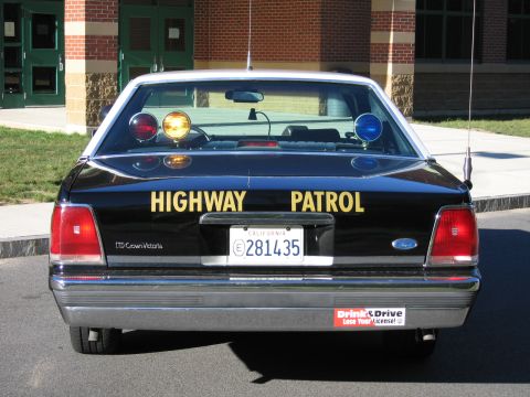 1991 Ford LTD Crown Victoria - Direct rear view of a black Highway Patrol LTD Crown Victoria sedan with an illuminated amber roof beacon and California plate 281435.