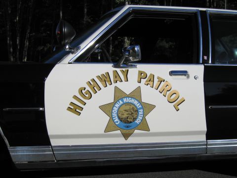 1991 Ford LTD Crown Victoria - Close-up of a white car door with HIGHWAY PATROL lettering arched over a gold California Highway Patrol star badge.