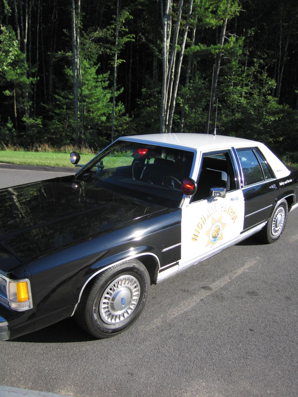High-angle front-quarter view of black-and-white highway patrol sedan