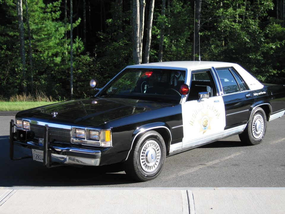 Black-and-white California Highway Patrol Ford sedan parked on roadside